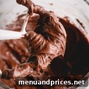 A small image of a paddle attachment covered in chocolate cream cheese frosting.