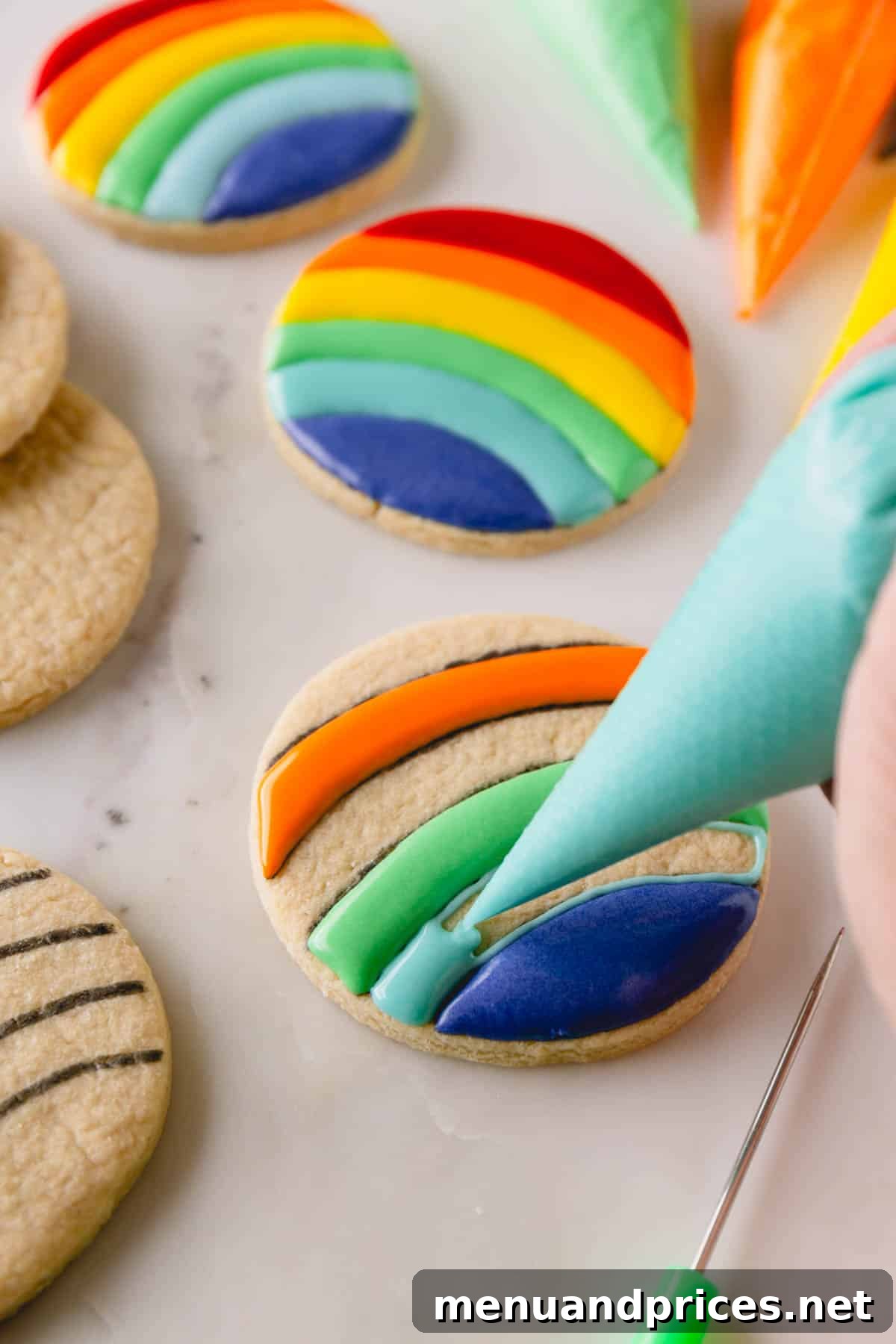 Mastering Royal Icing 11 Circular sugar cookies being decorated with rainbow royal icing, illustrating the outline and initial flood steps.