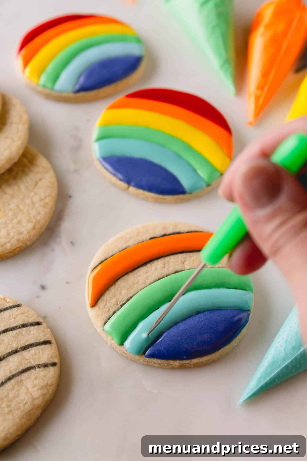 Mastering Royal Icing 12 Circular sugar cookies being decorated with rainbow royal icing, showing the filling process after outlining.