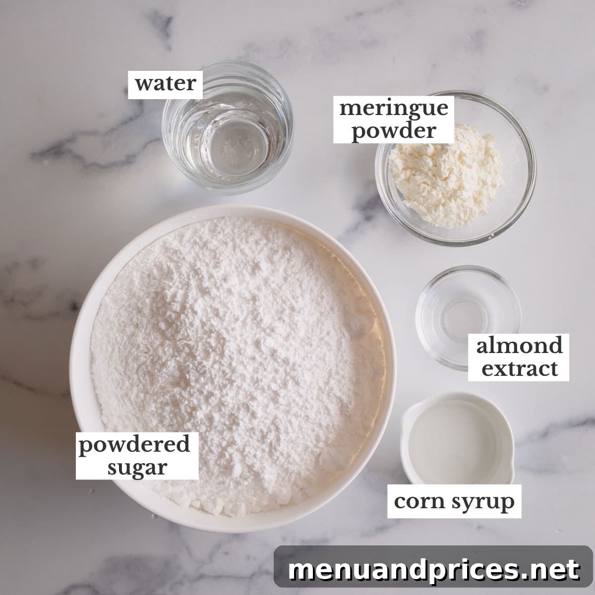 Mastering Royal Icing 4 A flat lay photograph displaying the key ingredients for royal icing: water, powdered sugar, meringue powder, corn syrup, and almond extract.