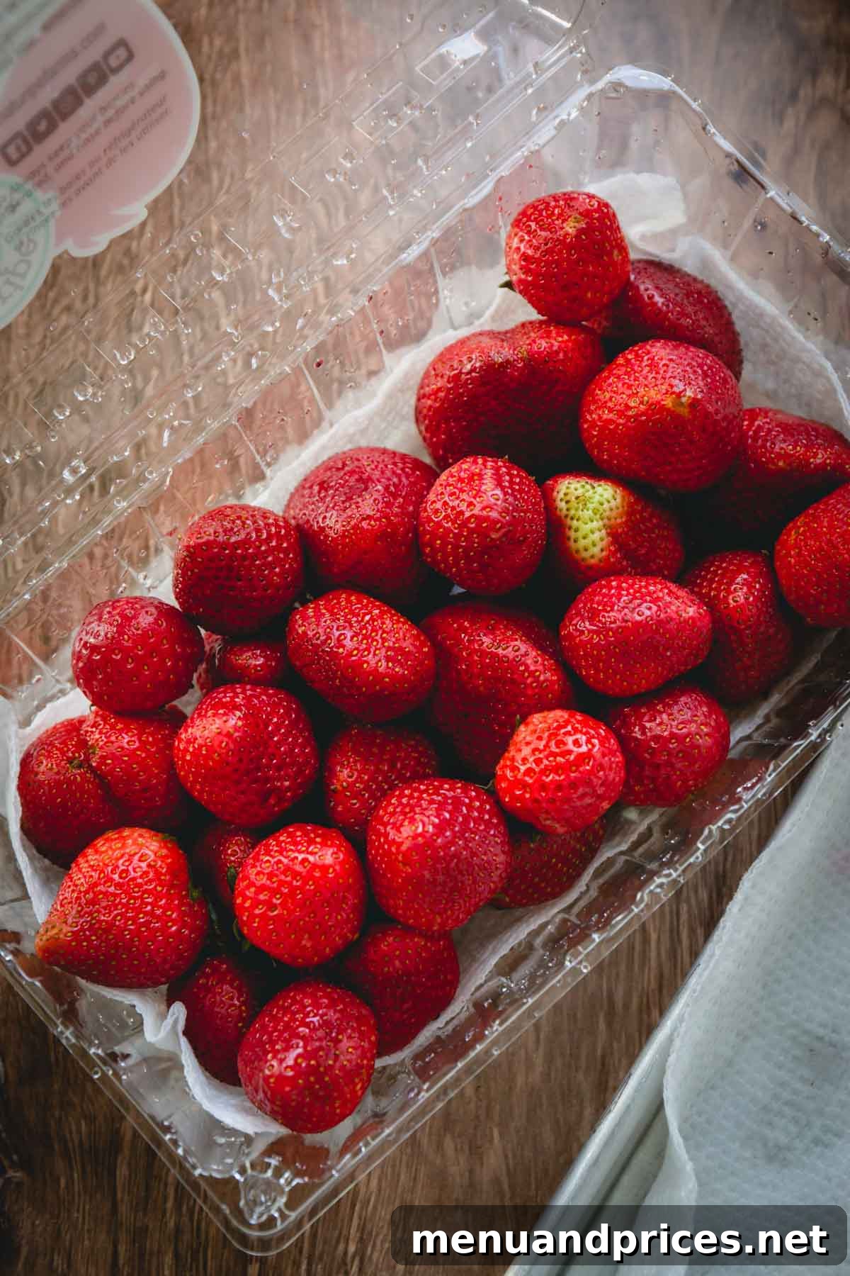 Prepare Strawberries for Extended Freshness 4 A paper towel-lined plastic clamshell container filled with perfectly clean, fresh strawberries, ready for refrigerator storage.
