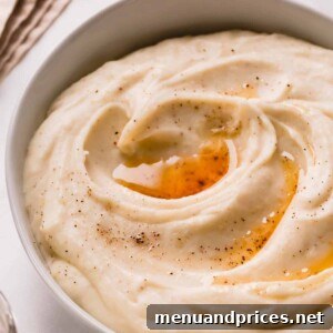 A bowl of brown butter mashed potatoes topped with brown butter and black pepper.