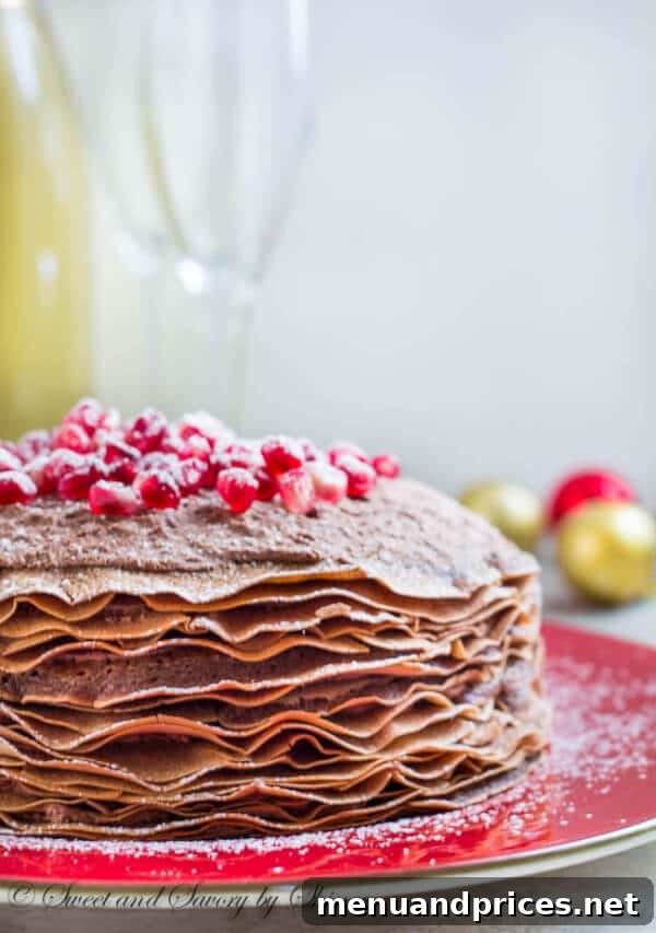 A beautifully presented slice of chocolate mousse crepe cake showing its intricate layers and creamy filling, adorned with fresh pomegranate seeds.