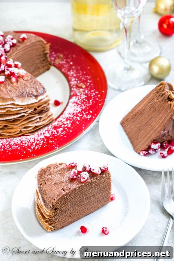 Chocolate Mousse Crepe Cake, a close-up of the top layer adorned with fresh pomegranate seeds and a dusting of powdered sugar.