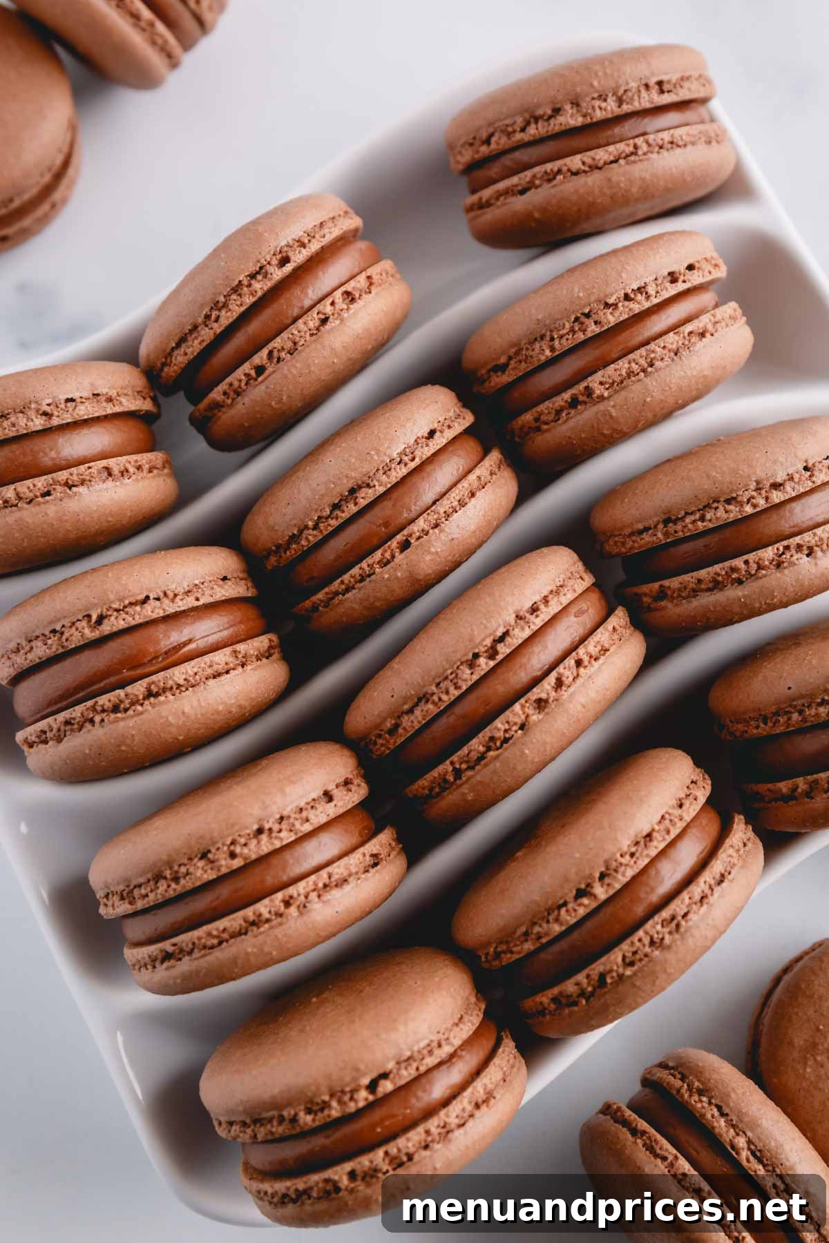 Heavenly Chocolate Macarons 3 A cluster of chocolate macarons generously filled with a creamy chocolate ganache, presented on an elegant white serving platter.