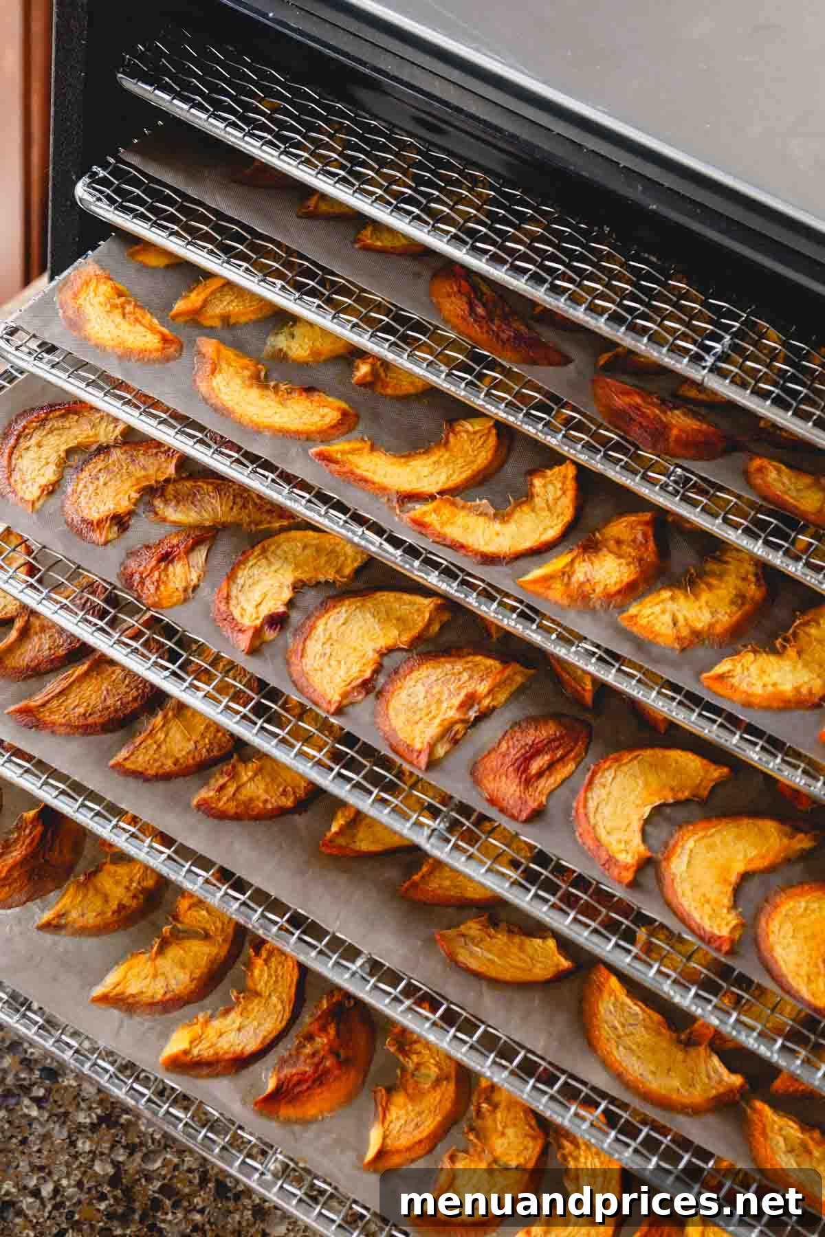A food dehydrator with five trays filled with peaches in various stages of dehydration.