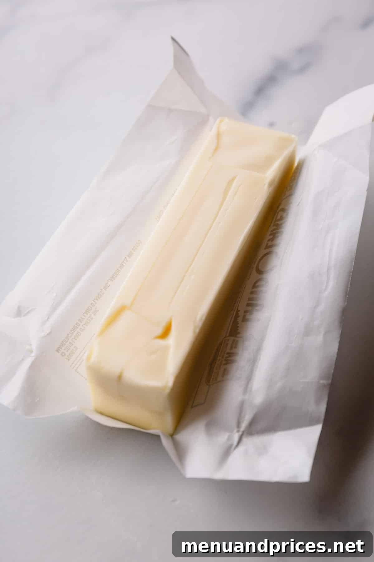 A pristine stick of unwrapped butter, perfectly at room temperature, symbolizing readiness for optimal baking.