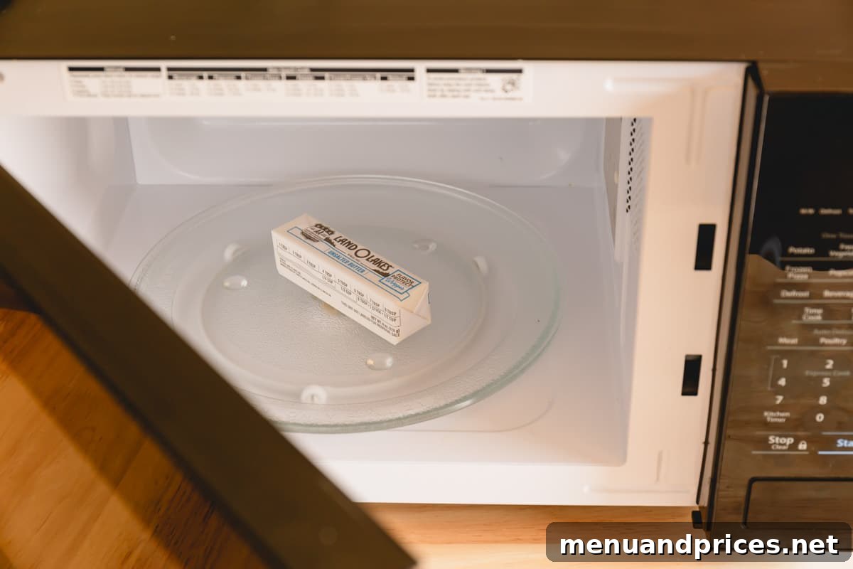 A stick of butter, still encased in its wrapper, carefully placed inside a microwave, illustrating the proper setup for the rapid softening technique.
