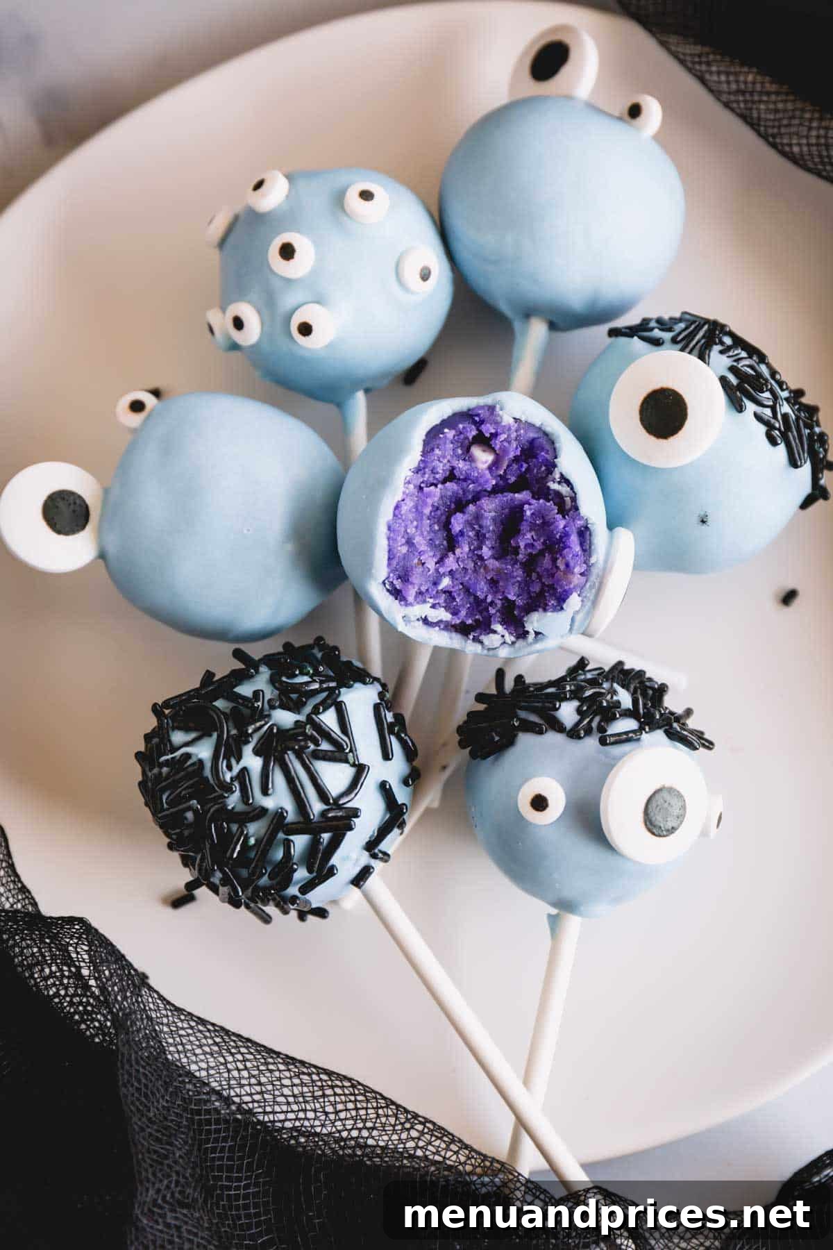 Vibrant blue monster cake pops with an assortment of candy eyes and sprinkle hair, one with a playful bite taken out.