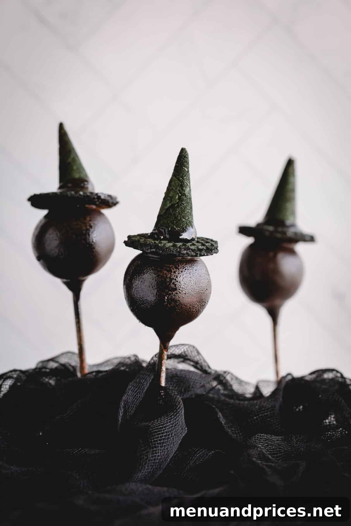Three chocolate cake pops adorned with whimsical witch hats, perfect for a spooky treat.