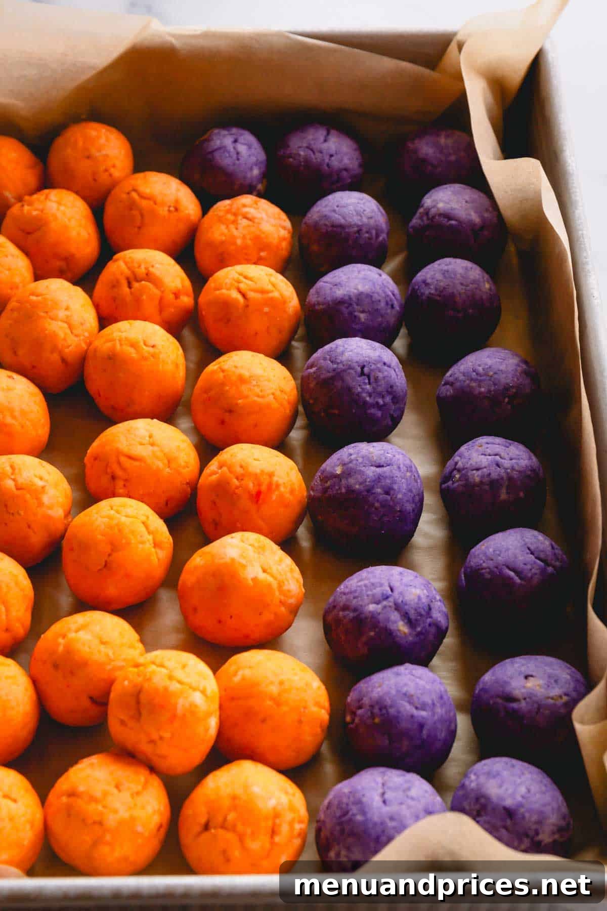 Orange and purple cake pop balls neatly arranged on parchment paper in a tray, ready for the next step.
