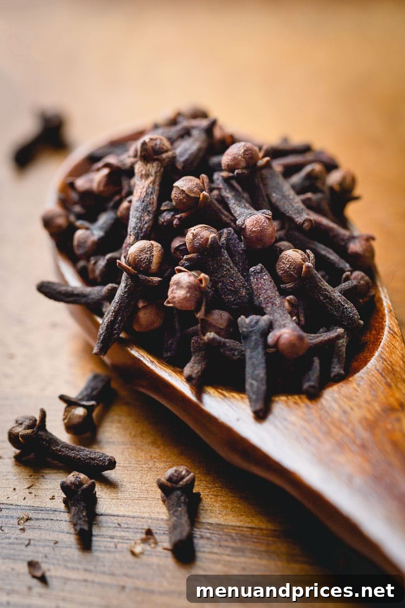 Crafting the Ultimate Mulled Wine 3 A close-up image of whole cloves resting on a rustic wooden spoon, emphasizing their natural form for mulling.