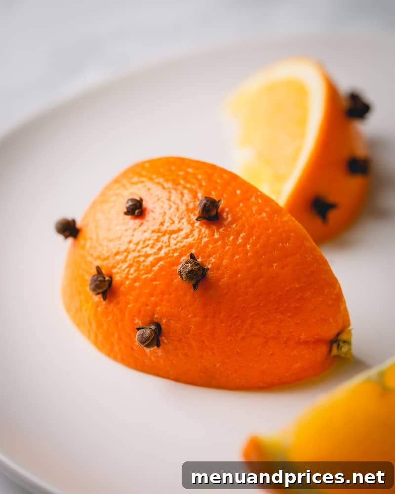Crafting the Ultimate Mulled Wine 4 A vibrant wedge of orange intricately studded with whole cloves, ready to infuse flavor into the mulled wine.