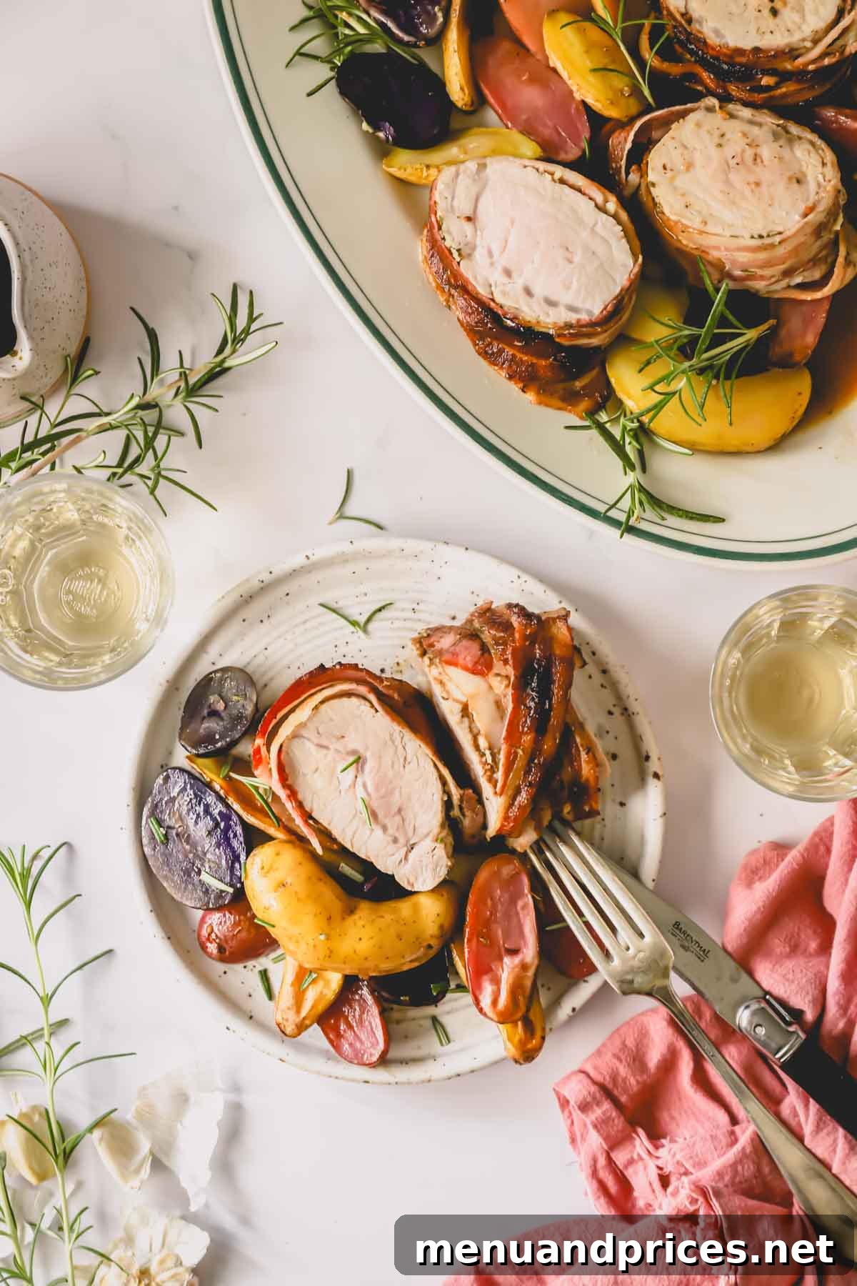 The Ultimate Bacon-Wrapped Pork Tenderloin 11 A plate of bacon wrapped pork tenderloin and roasted potatoes next to a large serving platter.