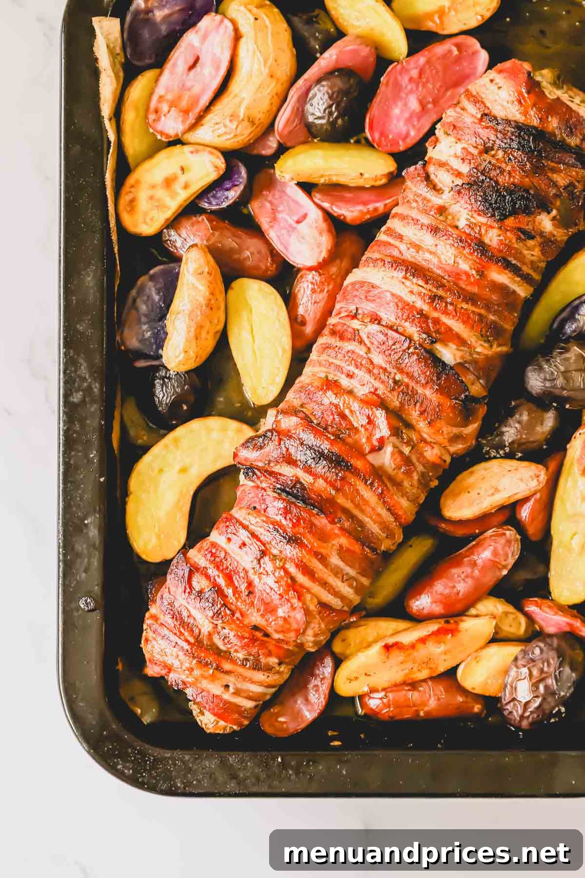 The Ultimate Bacon-Wrapped Pork Tenderloin 3 A baking tray with a full bacon wrapped tenderloin and roasted potatoes.