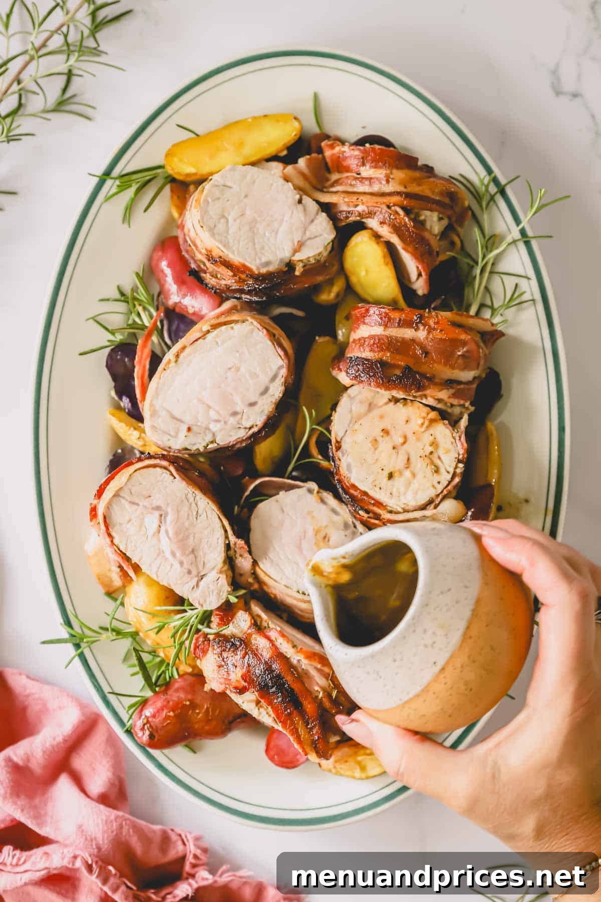 The Ultimate Bacon-Wrapped Pork Tenderloin 10 A platter of bacon wrapped pork tenderloin with a hand pouring sauce on top for serving.