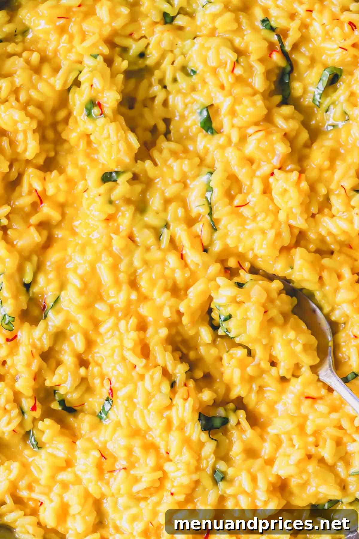Express Golden Saffron Risotto 3 Close-up view of creamy saffron risotto with a spoon lifting a scoop, highlighting its perfect texture.