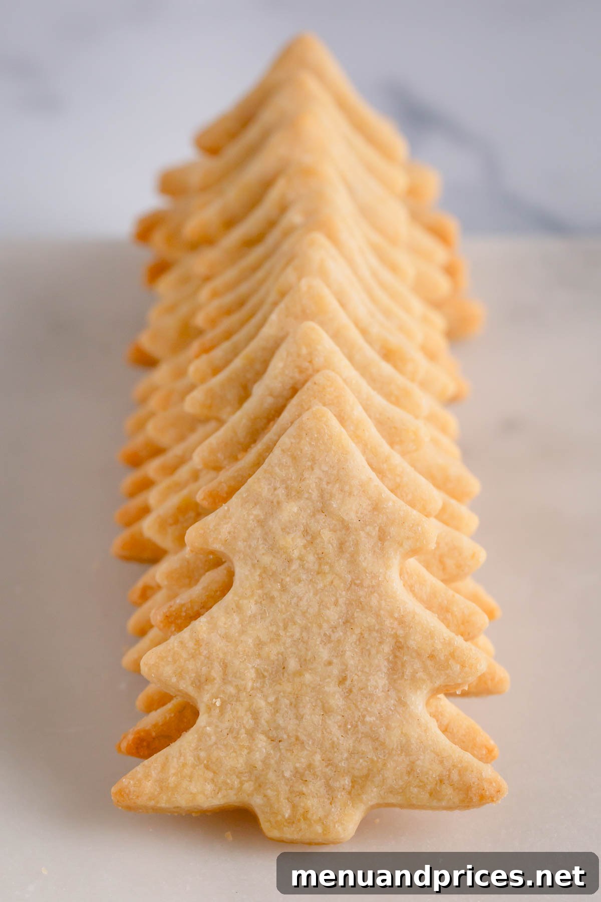 Festive Frosted Delights 3 A stack of perfectly baked sugar cookies shaped like Christmas trees, ready for decoration.