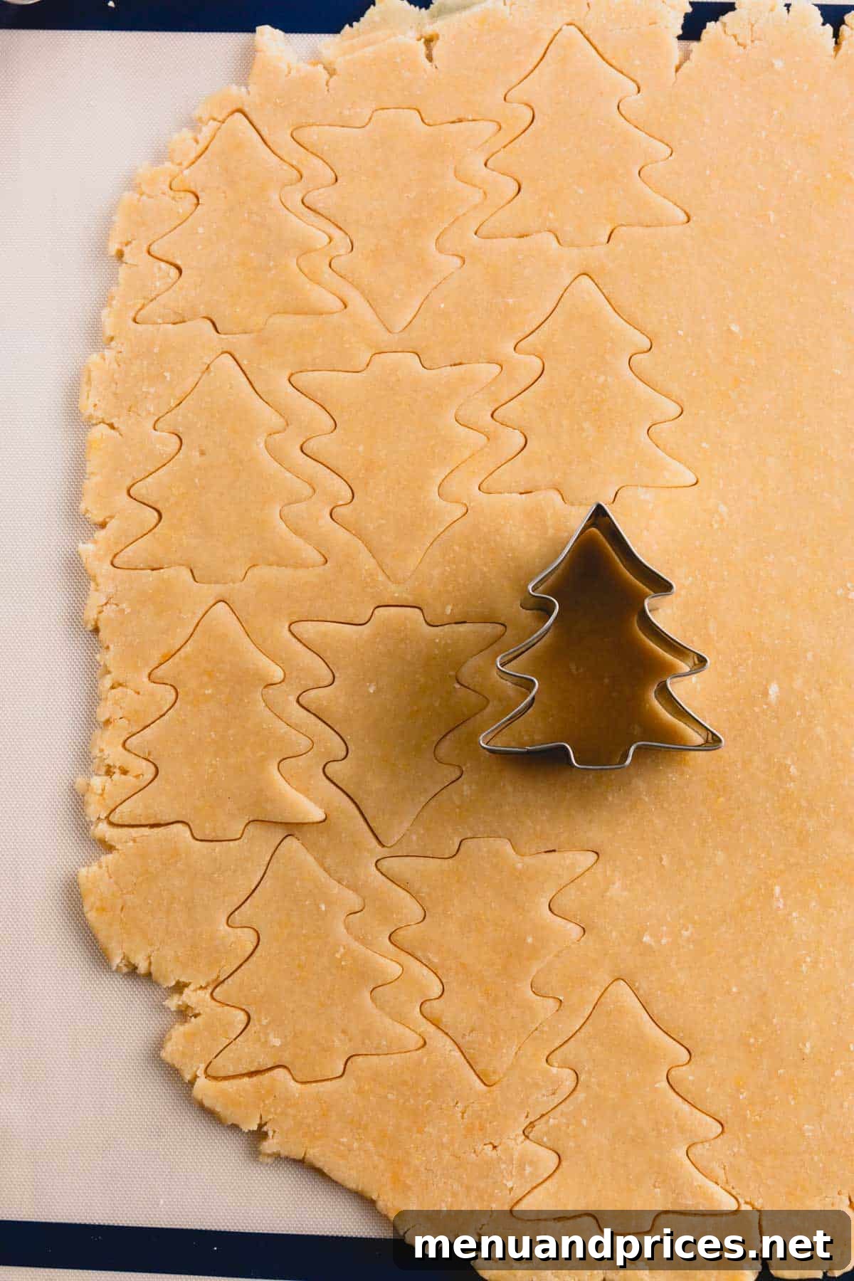 Festive Frosted Delights 6 Sugar cookie dough being meticulously cut into a Christmas tree shape with a cookie cutter.