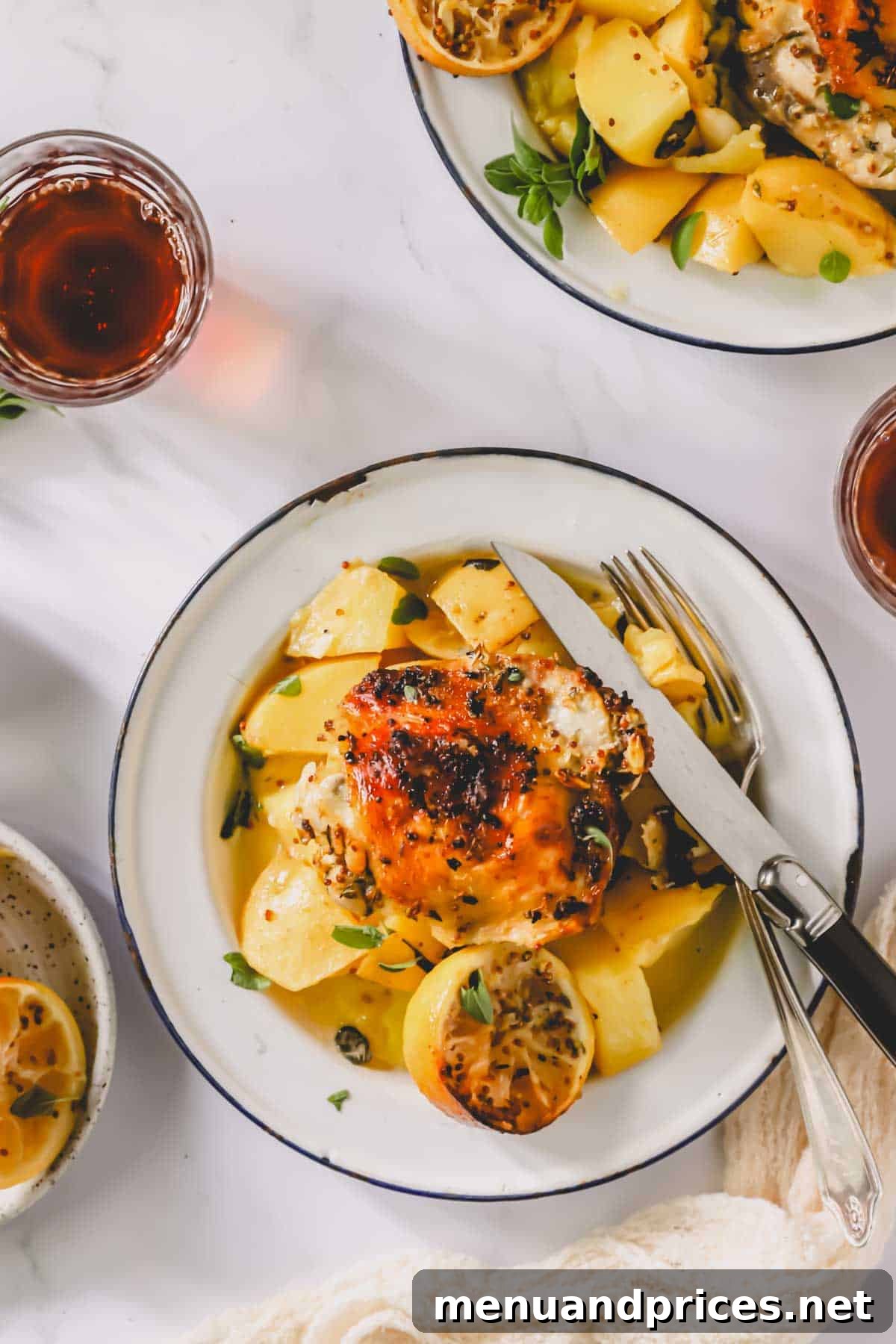 A plate of Greek lemon chicken and potatoes with a knife and fork elegantly placed on top, ready to be enjoyed.