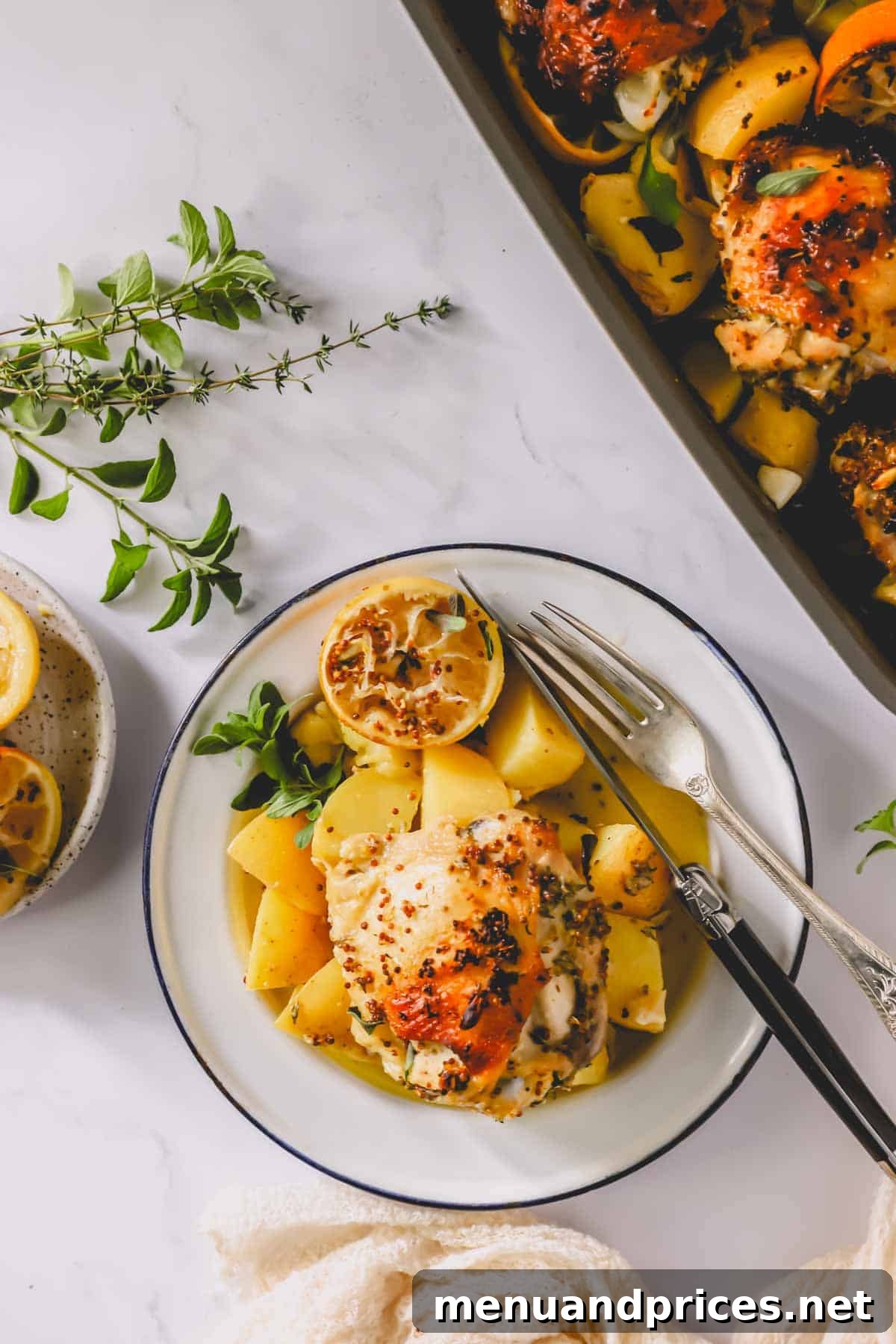 A stunning arrangement featuring a plate of Greek lemon chicken and potatoes next to the full baking dish, showcasing the abundant and delicious meal.