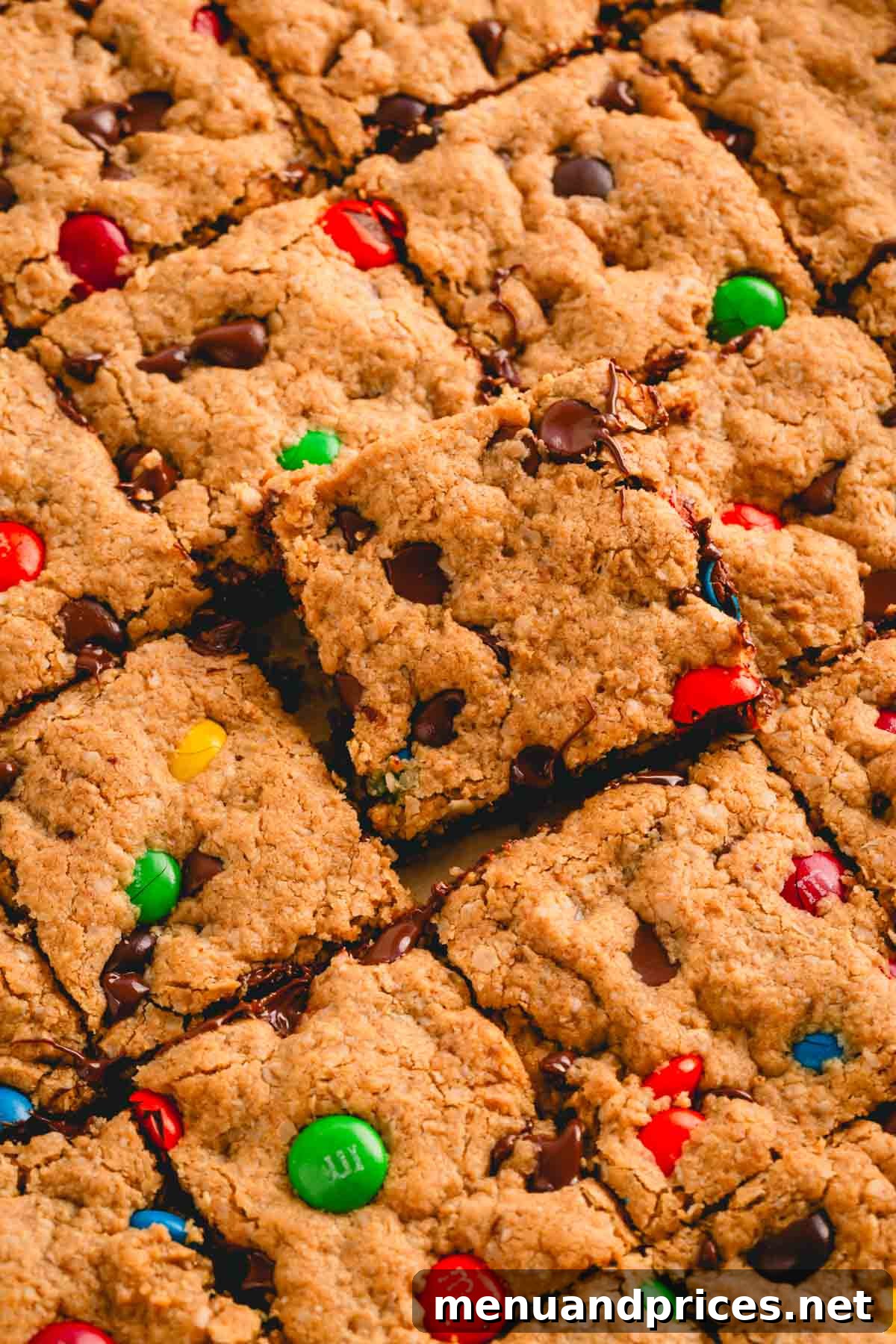 Kitchen Sink Cookie Squares 7 A close-up shot of perfectly sliced flourless monster cookie bars, with one bar slightly elevated to show its rich texture.