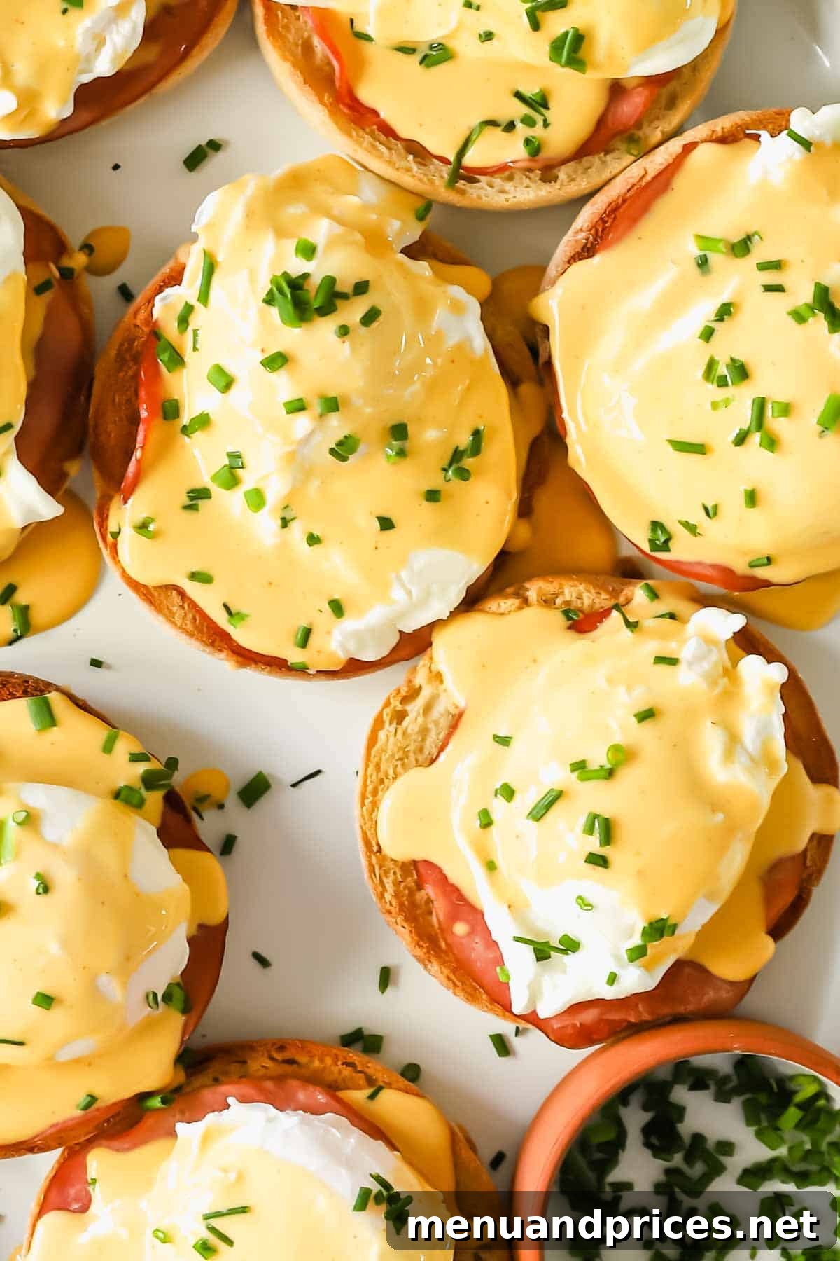 The Ultimate Eggs Benedict with Handcrafted Hollandaise 9 A close-up view of Eggs Benedict generously topped with fresh chives, highlighting the rich hollandaise and golden yolk.