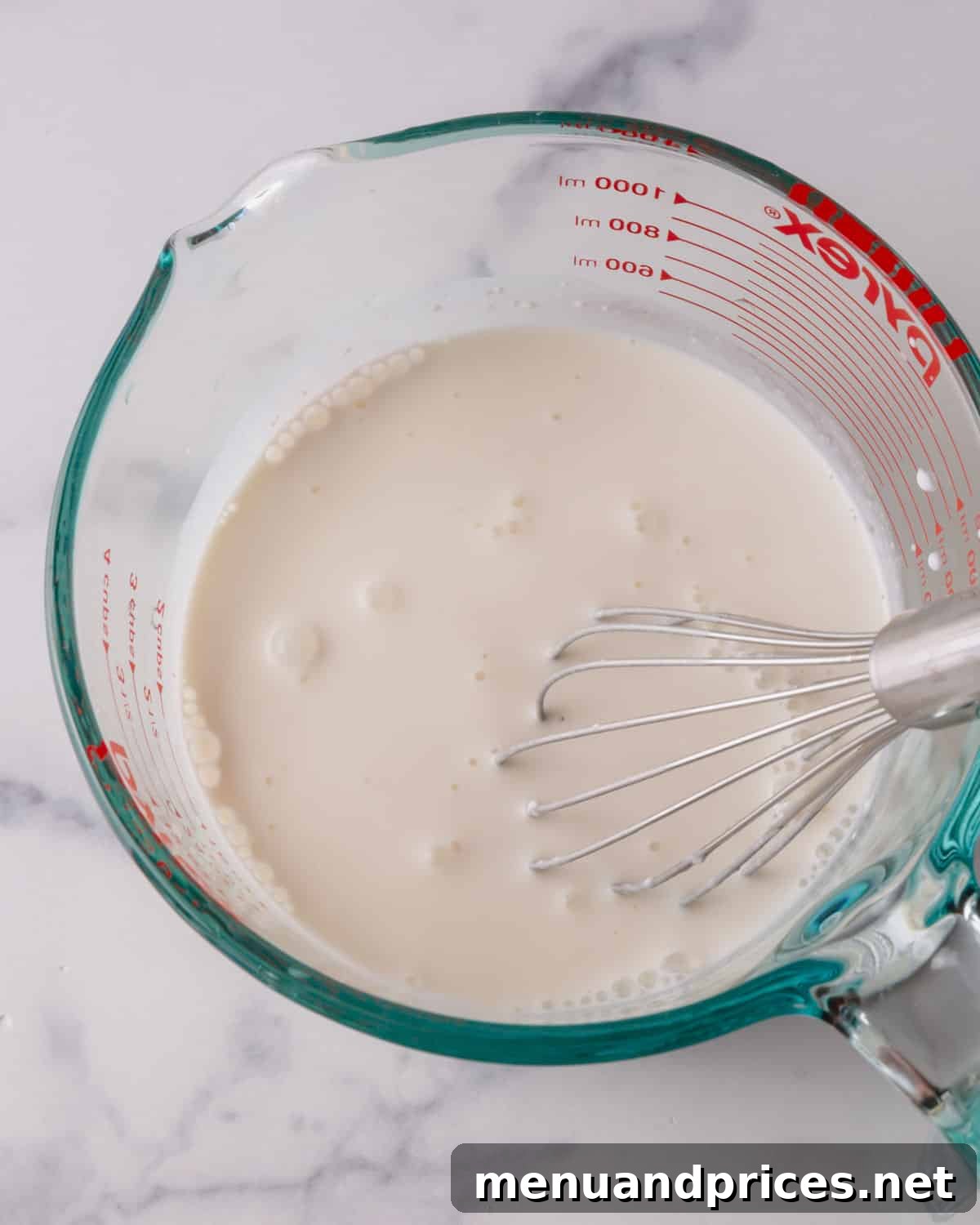 Fluffy White Cake Perfection 6 Wet ingredients for cake being whisked smoothly in a liquid measuring cup, ready for incorporation.