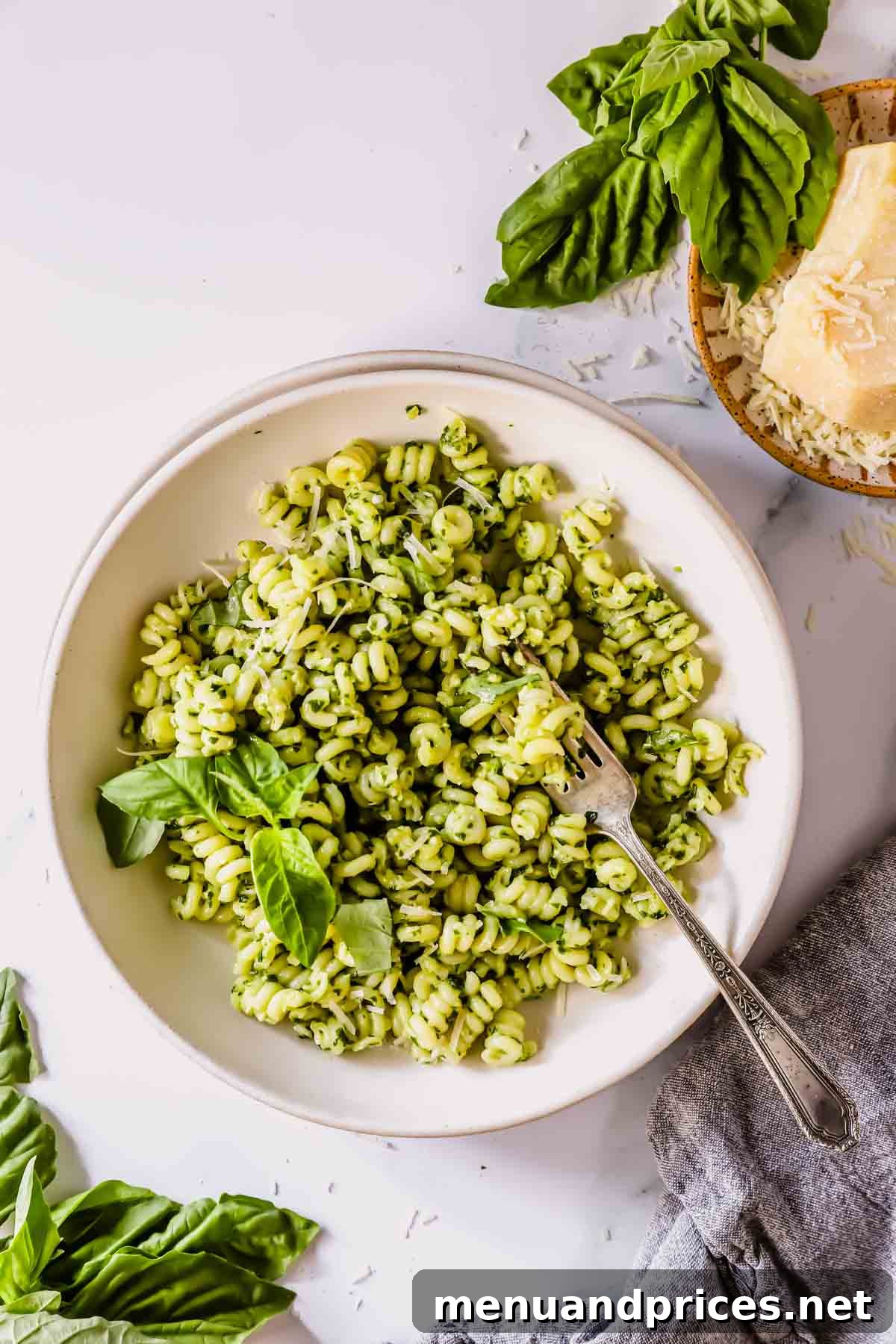 A bowl of basil pesto pasta with a fork on top.
