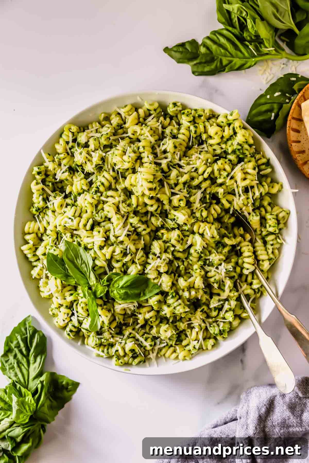 A bowl of basil pesto pasta with two forks sticking out.