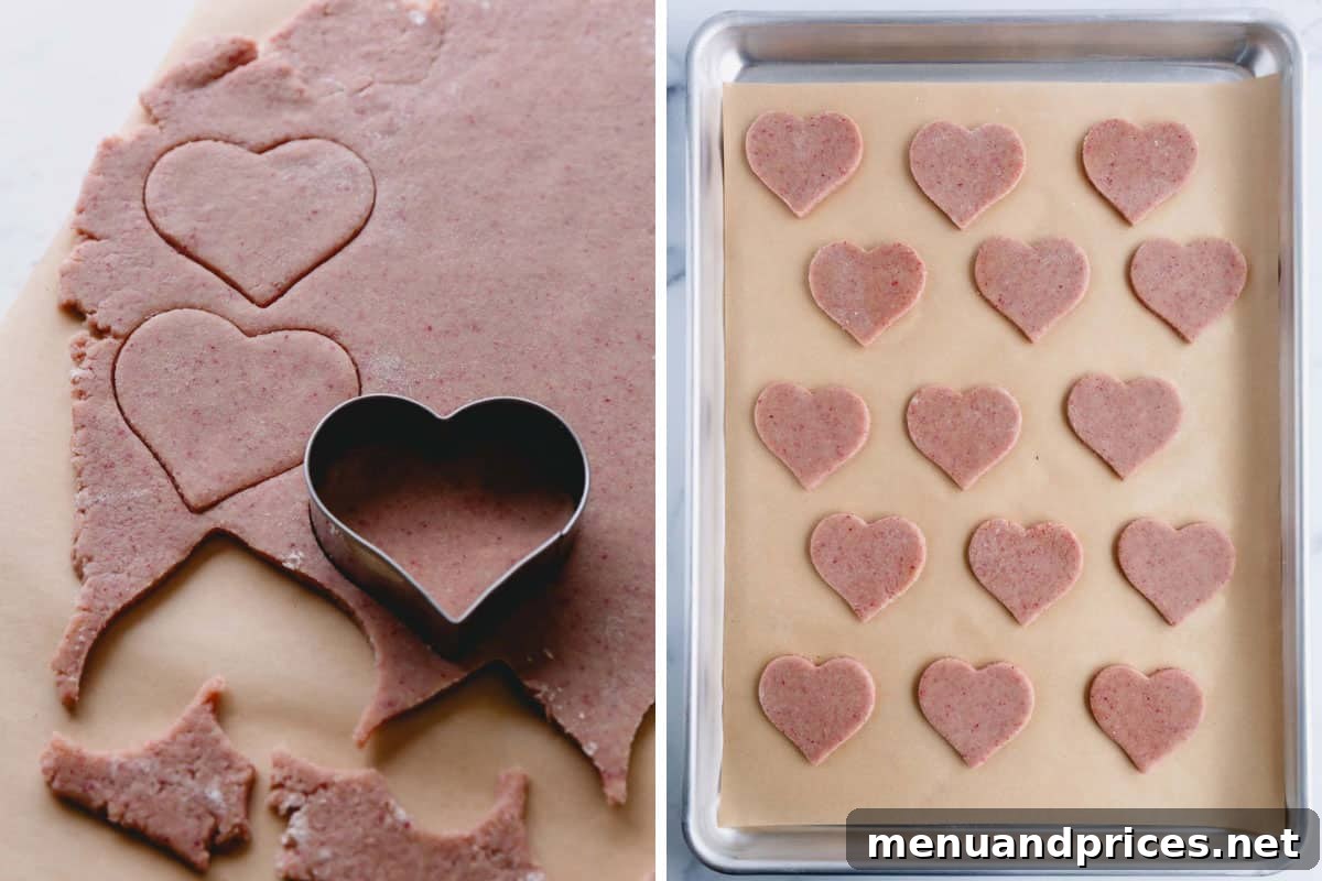 Raspberry Dream Cookies 7 A heart-shaped cookie cutter in pink dough, and several cut-out cookies arranged on a lined baking sheet.