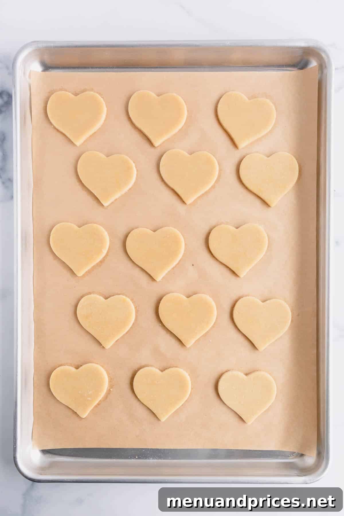 Sweetheart Sugar Cookie Delights 4 Heart-shaped sugar cookies on a parchment paper lined baking sheet.