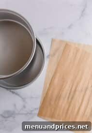 Achieving the Ideal Parchment Fit for Round Cake Pans 3 Two stacked round cake pans alongside two sheets of parchment paper, highlighting the simple tools needed.