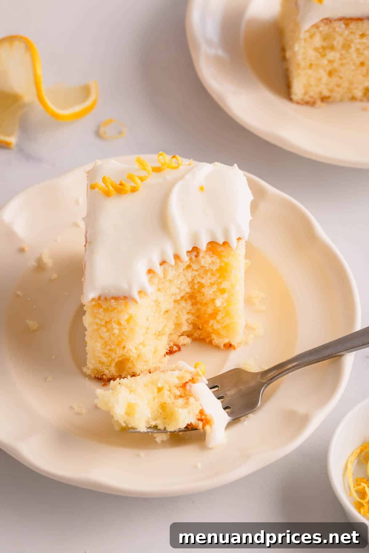 Sunshine Lemon Sheet Cake 13 A delectable slice of frosted lemon sheet cake gracefully placed on a white plate, with a fork holding a perfect bite, ready to be savored.