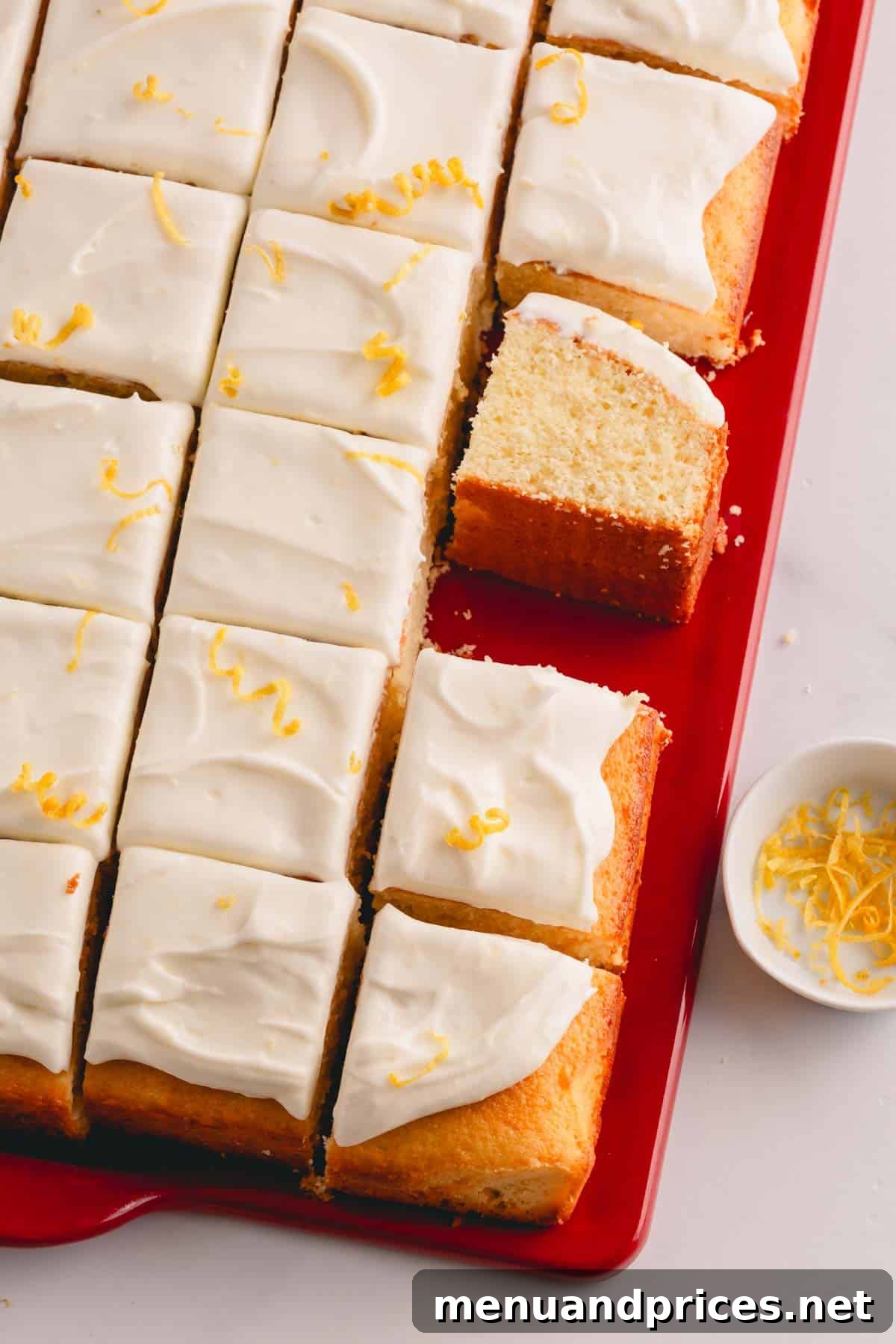Sunshine Lemon Sheet Cake 3 A whole lemon sheet cake, beautifully frosted with lemon cream cheese frosting, meticulously sliced into perfect squares and arranged on a serving platter.
