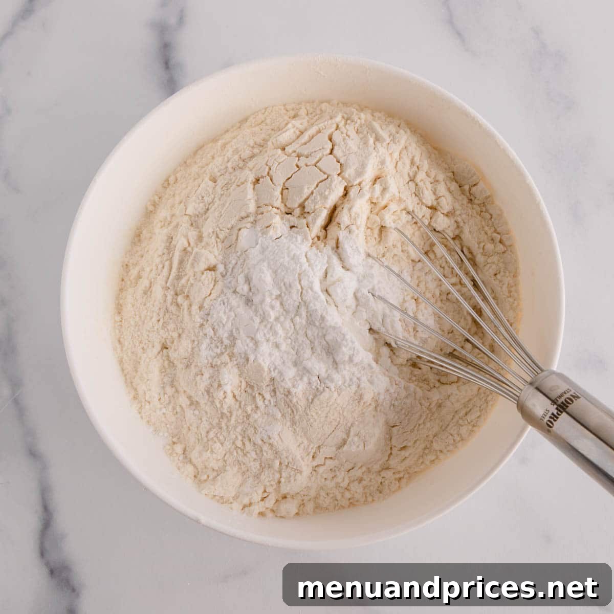 Sunshine Lemon Sheet Cake 5 A close-up view of dry ingredients, including flour, baking powder, and salt, being vigorously whisked together in a medium bowl to ensure even distribution.