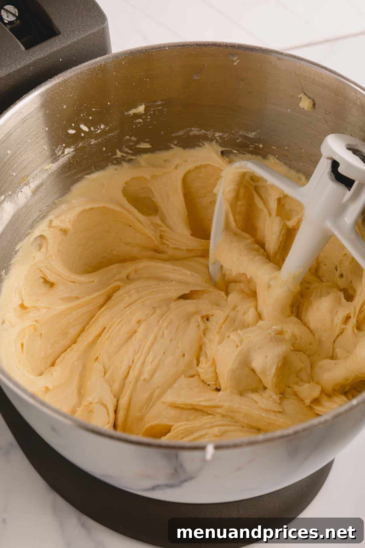 Sunshine Lemon Sheet Cake 8 Close-up of fluffy and vibrant lemon sheet cake batter resting in a stand mixer bowl, perfectly mixed and ready for baking.