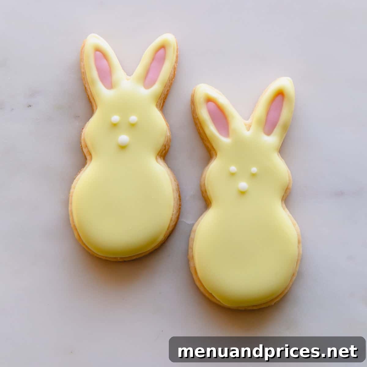 Two cheerful yellow Easter bunny sugar cookies with pink ears and expressive white eyes and noses, showcasing Method 1 decorating.