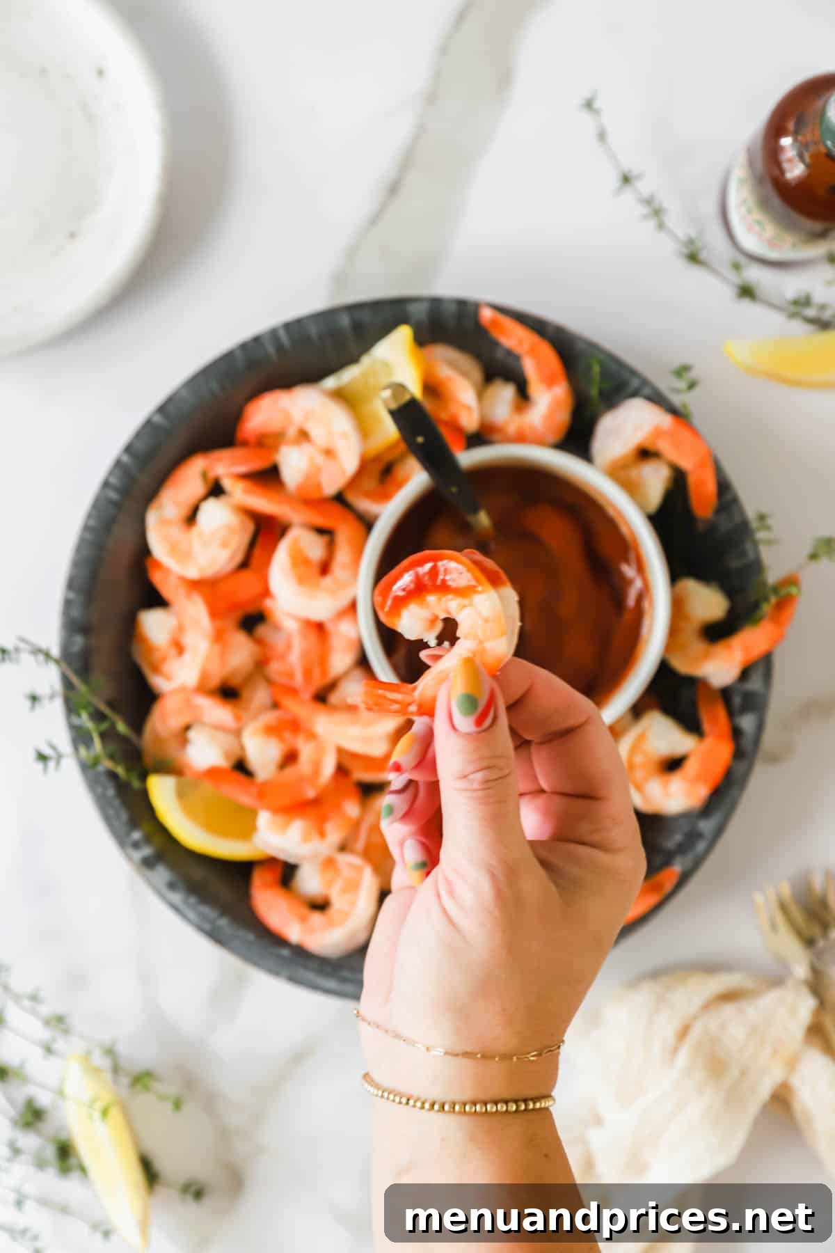 Zesty Prawn Cocktail 4 A hand holding a plump, perfectly poached shrimp, just dipped into a rich cocktail sauce, highlighting its succulent texture.