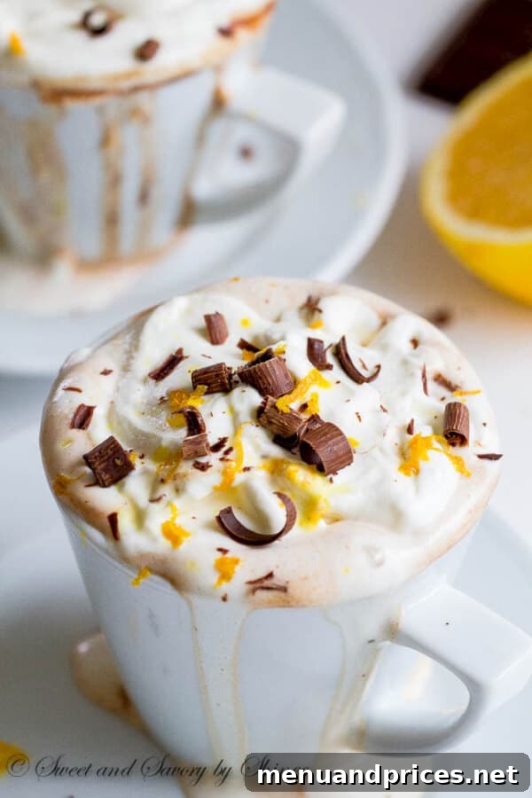 A top-down view of a cup of orange hot chocolate garnished with whipped cream and chocolate curls, inviting a warm and comforting sip.