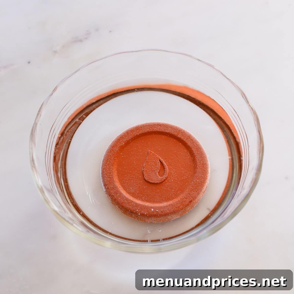 Rescue Your Hardened Brown Sugar 4 A round terra cotta disk fully soaking in a bowl of clear water, demonstrating the essential first step before using it to soften brown sugar.