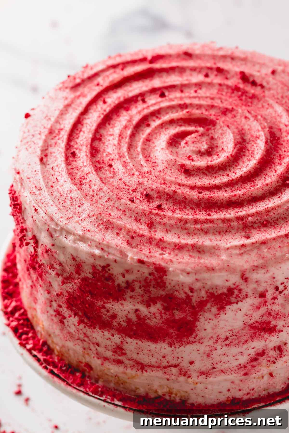 A beautifully frosted raspberry layer cake, lightly dusted with raspberry crumbs, ready for serving.