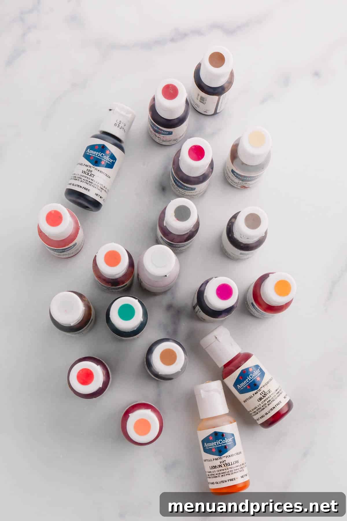 A vibrant collection of Americolor brand gel food colorings arranged on a luxurious marble background, showcasing a spectrum of intense hues ready to be used in baking projects.