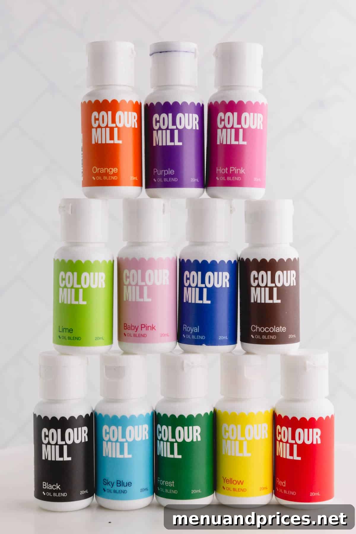 A collection of 12 colorful Color Mill brand oil blend food colorings elegantly stacked on top of each other, showcasing their vibrant pigments and professional packaging.