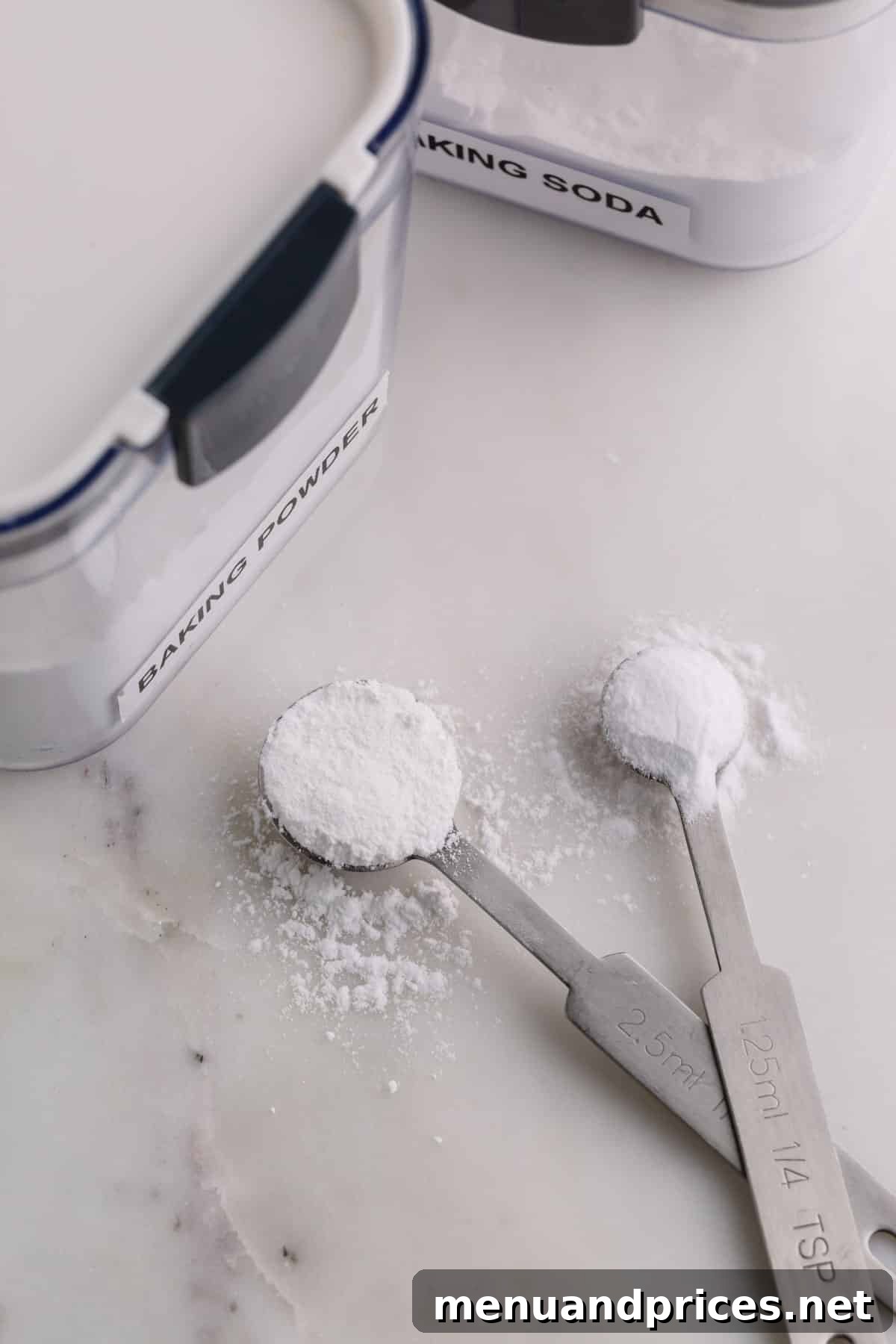 Baking Soda vs Baking Powder: Unraveling the Mystery 2 Two measuring spoons on a marble background, one with baking powder and one with baking soda.