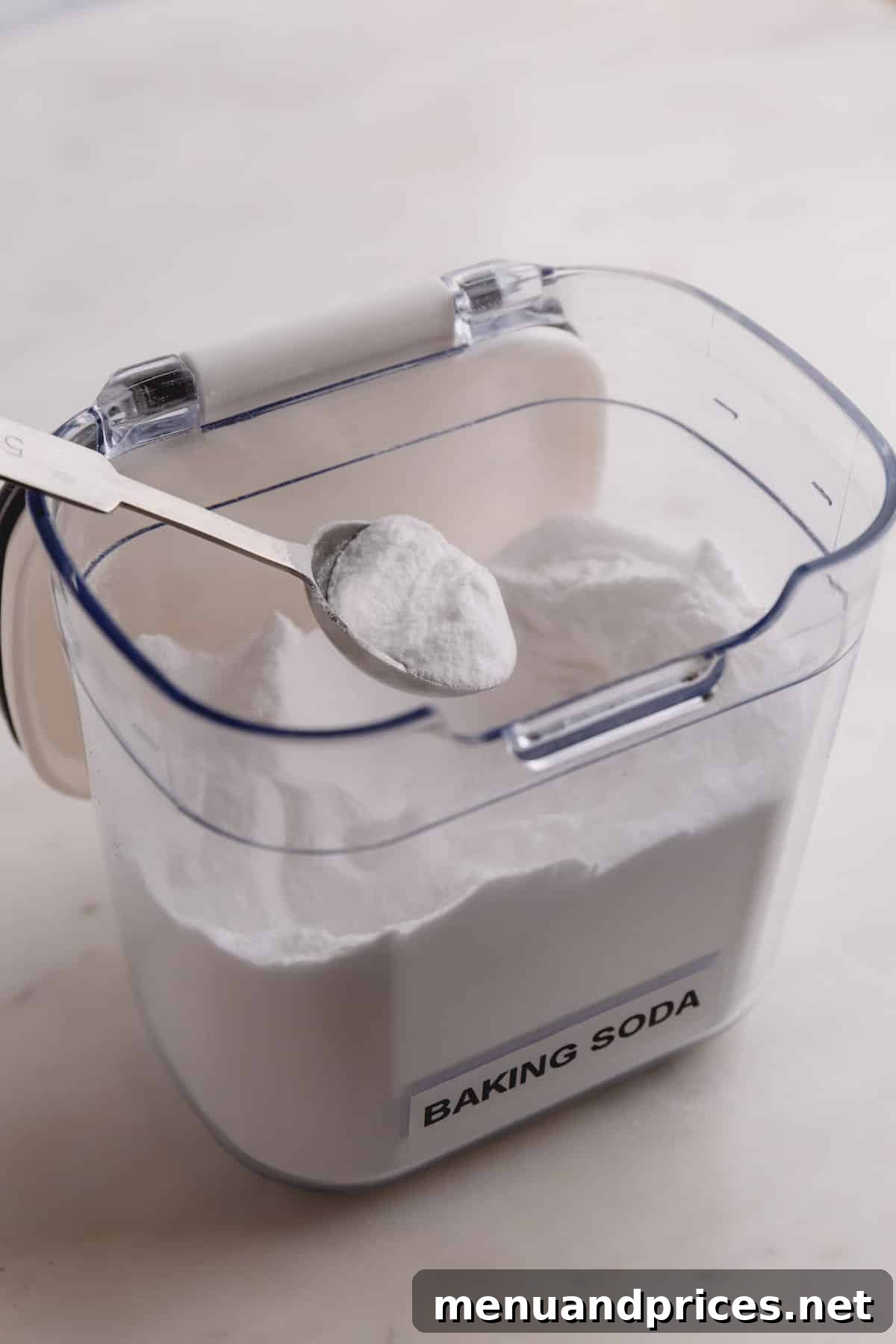 Baking Soda vs Baking Powder: Unraveling the Mystery 3 An open container of baking soda with a measuring spoon scooping out the powder.