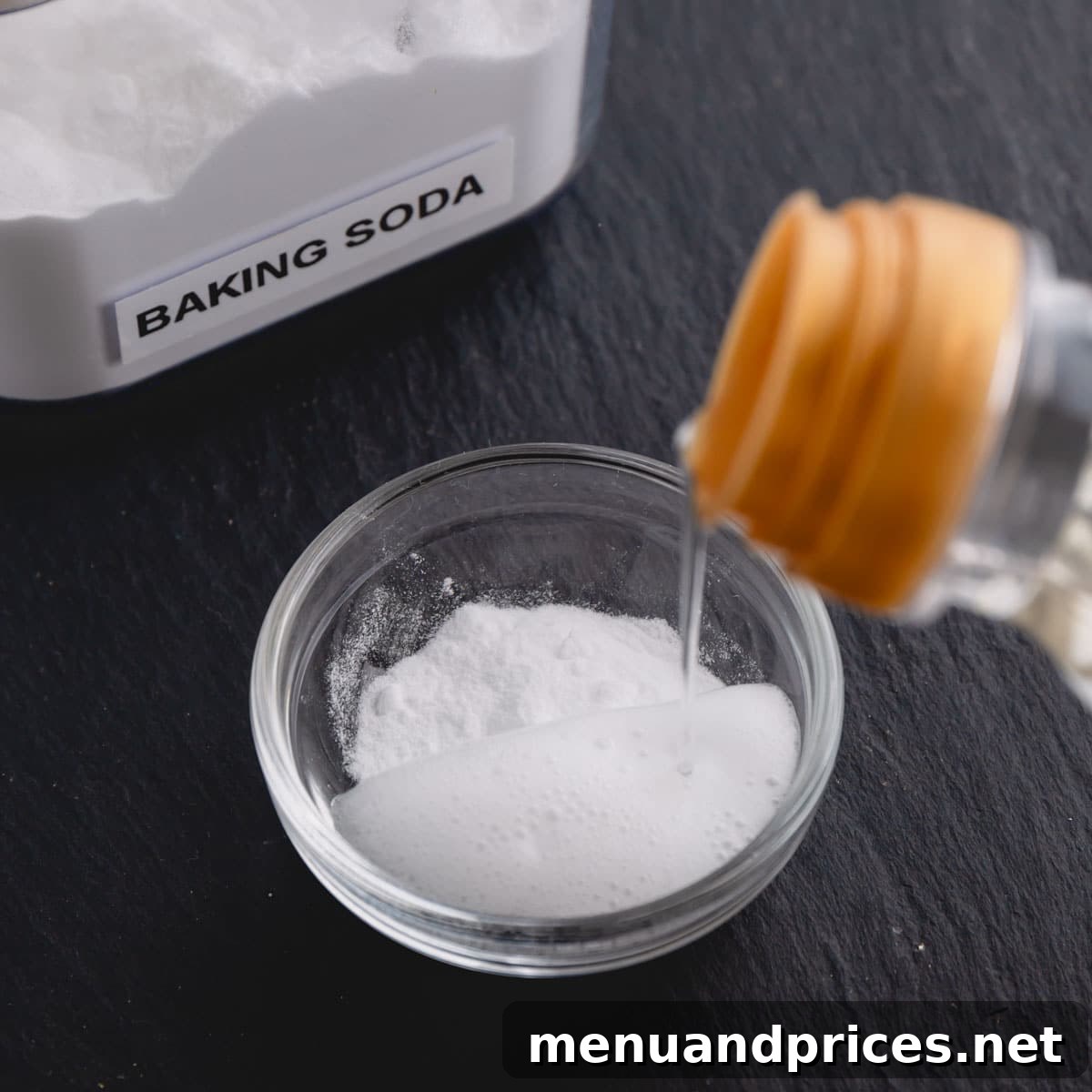 Baking Soda vs Baking Powder: Unraveling the Mystery 5 Vinegar being poured into a small glass dish with baking soda, causing the mixture to bubble up.