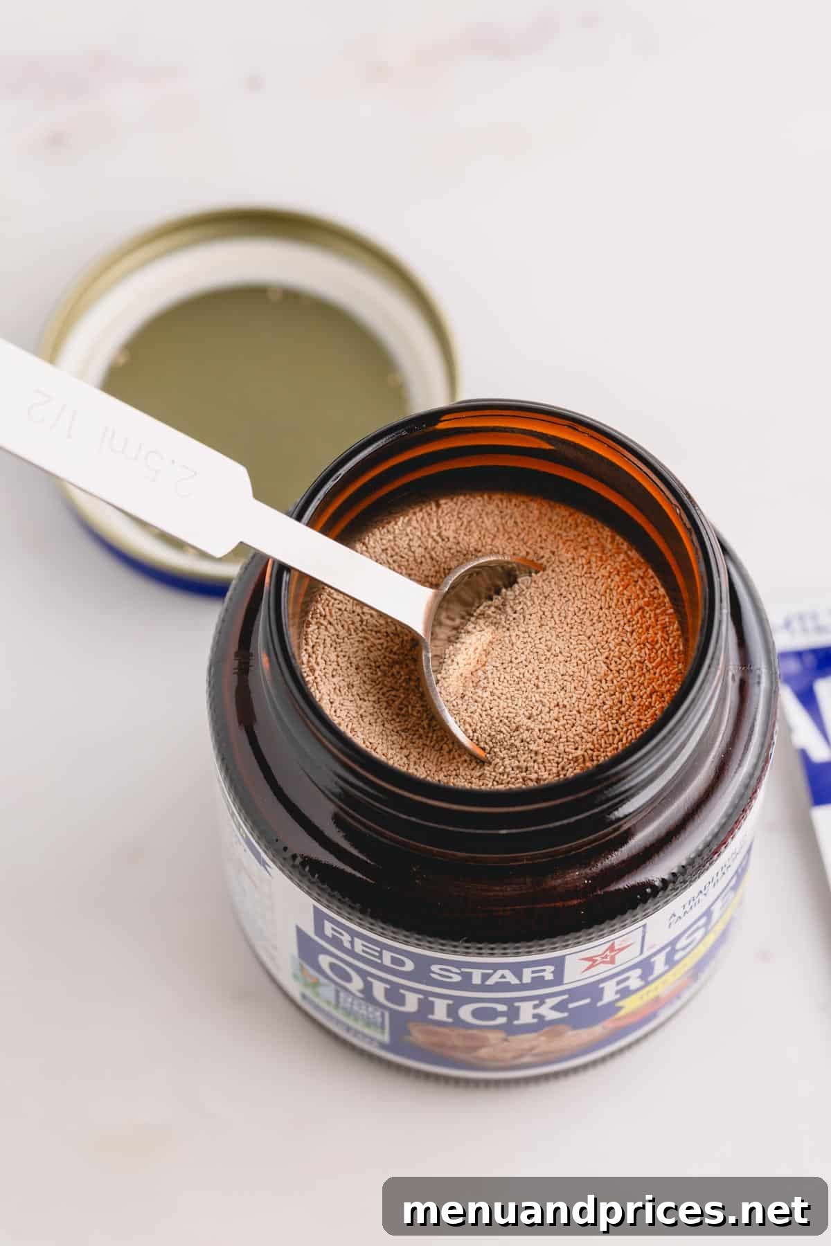 Yeast Essentials: Types and Their Ideal Uses 4 A clear glass jar of quick rise yeast with a measuring spoon resting inside, ready for use.