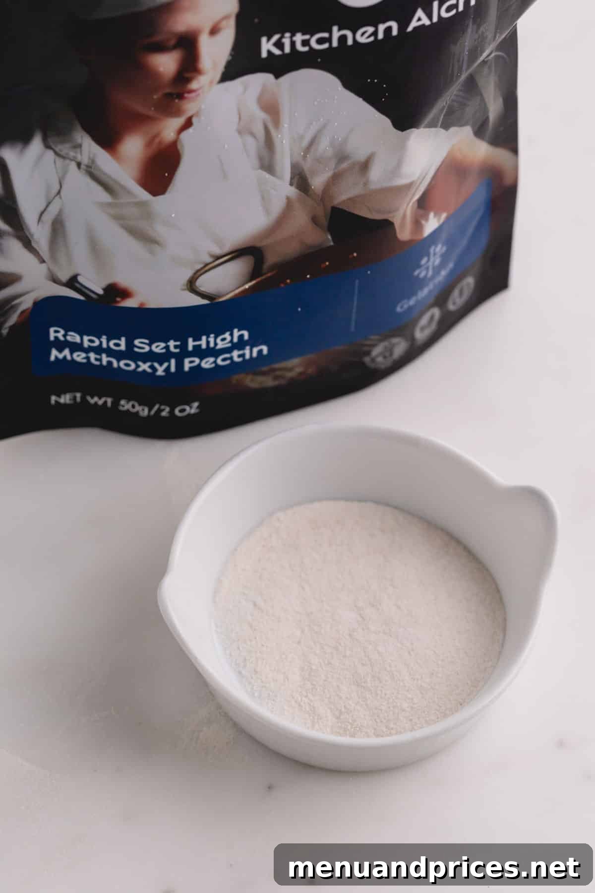 Mastering Thickening Agents 7 A small white dish filled with white pectin powder with the packet in the background, showing its typical commercial form.