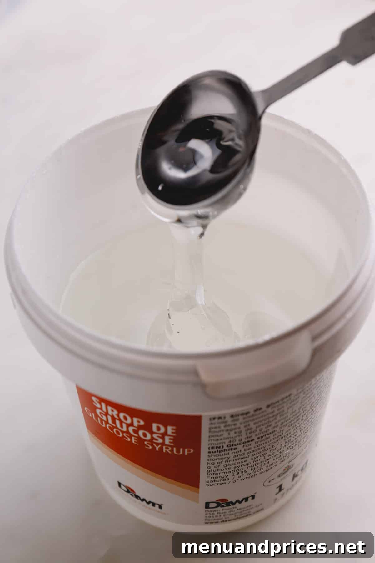 A tub of glucose syrup, showing its thick, clear consistency, used in professional baking.